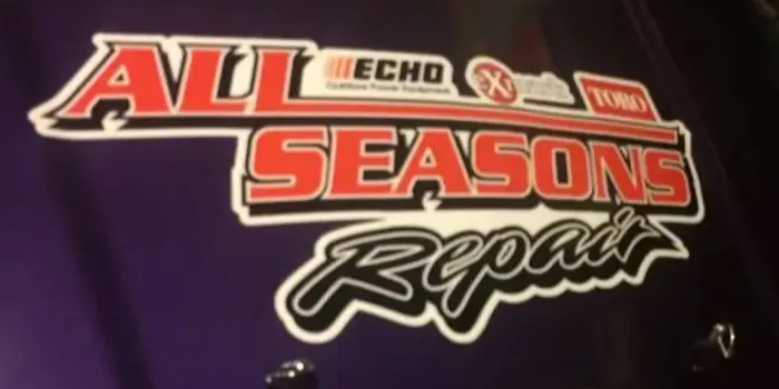 The ALL SEASONS Repair decal on the hood of the shop's own truck, in red and black block lettering