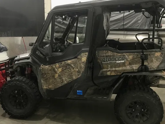 A Honda Pioneer 1000 side-by-side with a hard cab parked inside the All Seasons Repair shop
