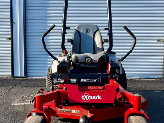 A red Exmark Radius 52 zero-turn mower photographed against the shop's ribbed steel overhead door
